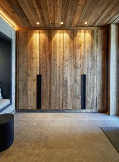 an empty room with wood paneling and lights on the walls, along with a bench