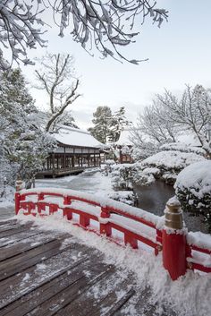 snow covers the ground next to a red bridge