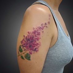 a woman's arm with purple flowers on the left shoulder and green leaves on the right arm