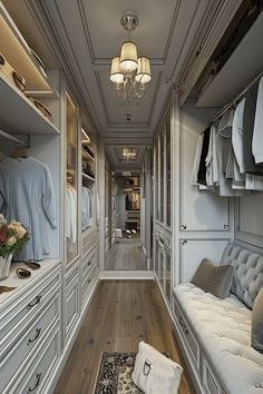 a walk - in closet with white furniture and wooden flooring, chandelier hanging from the ceiling