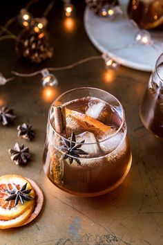 a drink in a glass with cinnamon stick garnishes on the rim next to other drinks