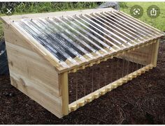 a wooden structure with metal slats attached to the roof and sides, in front of some grass