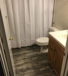 a white toilet sitting next to a bathroom sink under a shower curtain in a bathroom