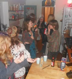 a group of women standing in a kitchen next to each other talking on cell phones