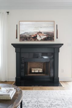 a living room with a fire place in the center and a painting on the wall