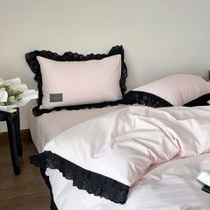 an unmade bed with pink and black pillows