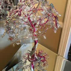 a tree made out of glass beads and other items on a table in front of a mirror