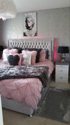 a bedroom with pink and grey bedding, black and white rugs and pictures on the wall