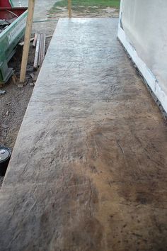 a wooden bench sitting in the middle of a dirt covered area next to a building