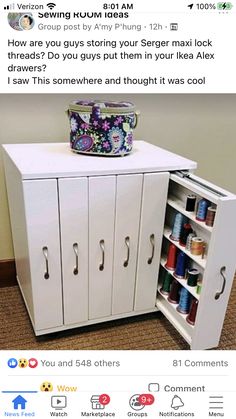 a white cabinet with two doors and some spools of thread on top of it