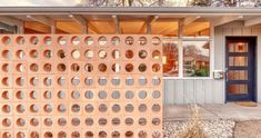 a house with many round holes on the front door and side wall that is made out of cement blocks