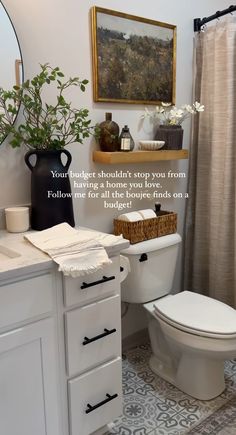 a white toilet sitting next to a bath tub in a bathroom under a framed painting