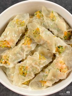 a white bowl filled with dumplings covered in cheese and broccoli florets