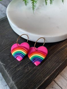 a pair of heart shaped earrings sitting on top of a wooden table