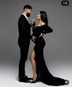 a man and woman standing next to each other in formal wear, posing for the camera