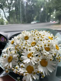 a bouquet of daisies sitting on the dashboard of a car