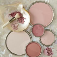 several different shades of pink and white paint in tins on top of a table