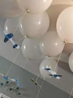 some white and blue balloons are hanging from the ceiling in an airplane - themed room