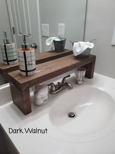 a bathroom sink with soap dispensers on the counter and a wooden shelf above it