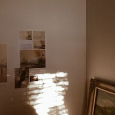 sunlight shining through the window onto a wall with pictures on it and a framed photograph