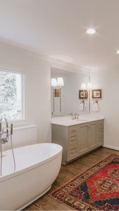 a large bathroom with a tub, sink and rug on the floor in front of it