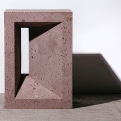 a concrete block with a hole in the middle and a shadow on the wall behind it