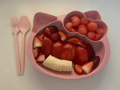 a pink plate with strawberries, bananas and other fruit in it next to a fork