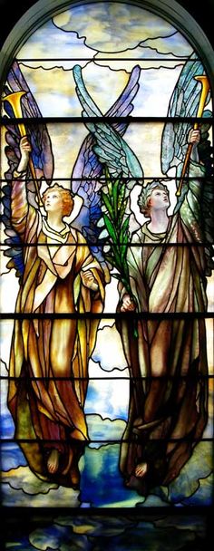 a stained glass window with two angels holding flowers in front of the sky and water