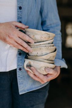 a person holding a stack of white cups