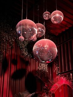 several disco balls hanging from the ceiling in a room with red lighting and palm trees