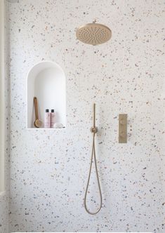 the shower head is mounted to the wall in this bathroom with speckles on the walls