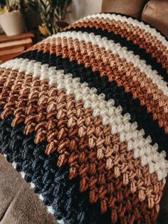 a crocheted blanket sitting on top of a couch next to a brown chair