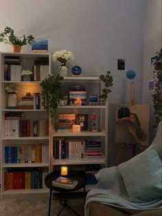 a living room filled with furniture and bookshelves next to a wall covered in plants