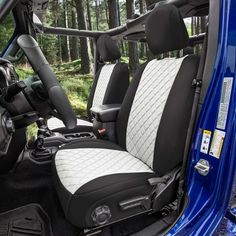 the interior of a vehicle with black and white leather upholstered seats, trees in the background