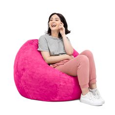 a woman sitting on a pink bean bag chair talking on her cell phone and laughing