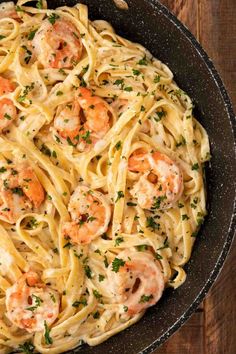 pasta with shrimp and parmesan cheese in a skillet on a wooden table