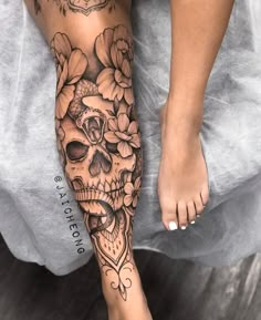 a woman's foot with a skull and flowers tattoo on the side of her leg