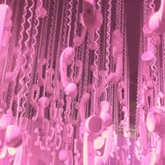 some pink lights hanging from the ceiling in front of a window with chains on it