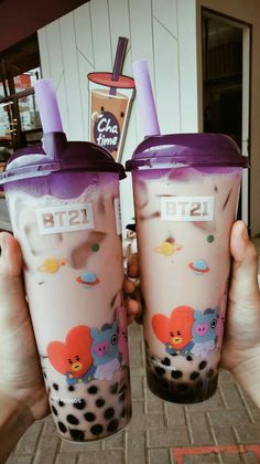 two people are holding up their cups with cartoon characters painted on the sides and purple rims