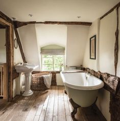 an old fashioned bathtub is in the middle of a bathroom with wood flooring