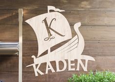 a wooden sign that says kaden with a boat on it