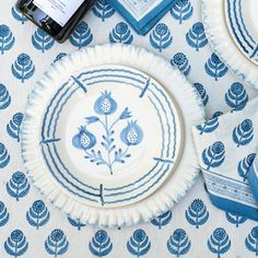 blue and white plates on a table with napkins next to a bottle of wine