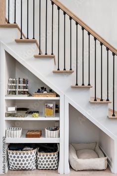 an under the stairs storage area with baskets and bookshelves in front of it