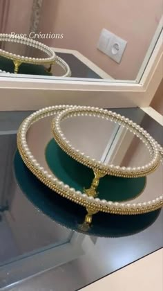 two green and white trays sitting on top of a glass table next to a mirror