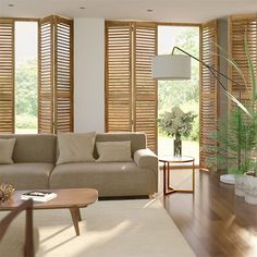 a living room filled with furniture and windows covered in wooden slatted shutters