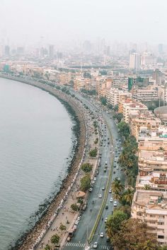 an aerial view of a city and the ocean with cars driving on it's side