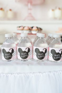 a table topped with water bottles filled with pink liquid and minnie mouse labels on them