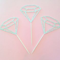 three diamond shaped cake toppers on a pink background