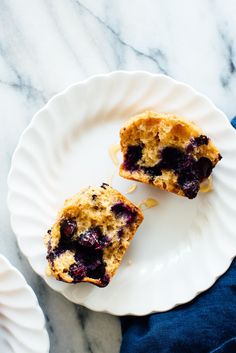 two blueberry muffins sitting on top of a white plate next to each other