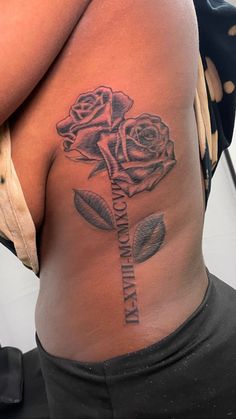 a woman with a rose tattoo on her lower back and the word love is written in cursive writing